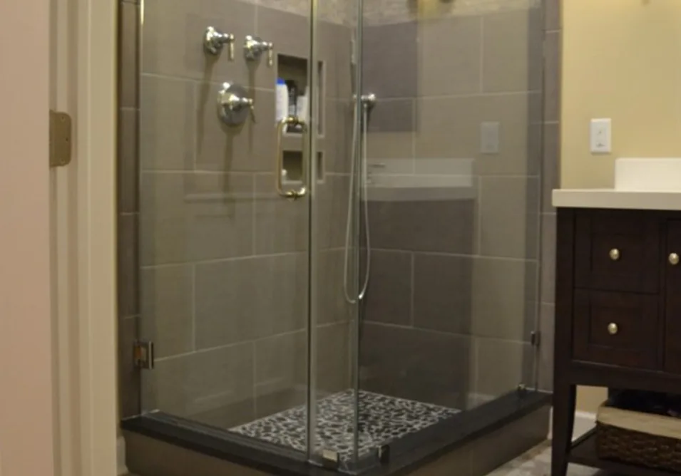 Tiled walk-in shower with a glass enclosure and a pebble floor