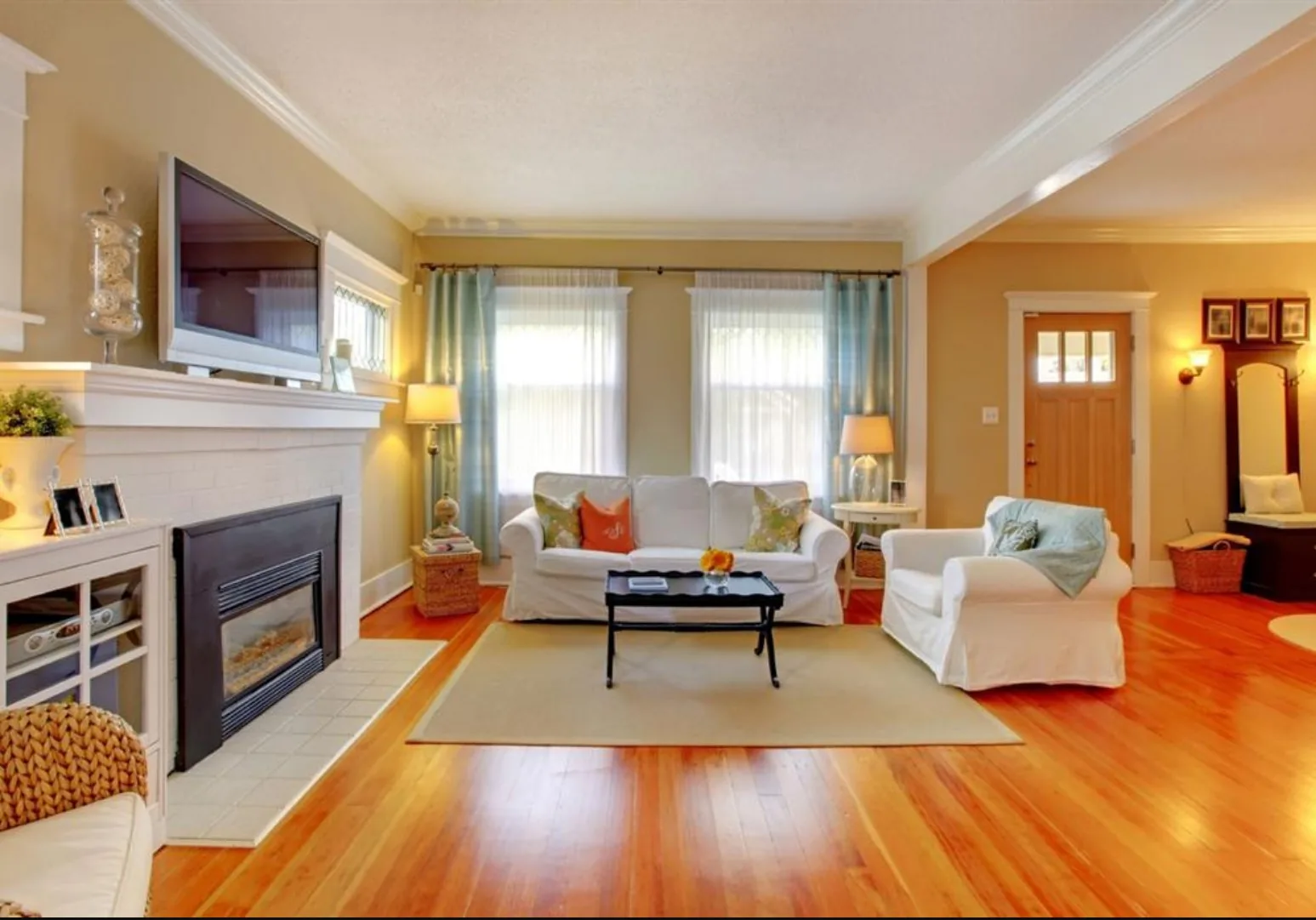 Living room with hardwood floors, crown molding, and a tiled fireplace